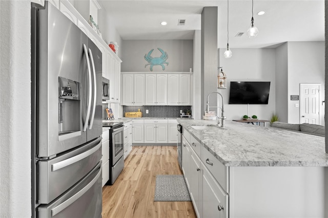 kitchen with light hardwood / wood-style floors, white cabinetry, decorative light fixtures, and appliances with stainless steel finishes