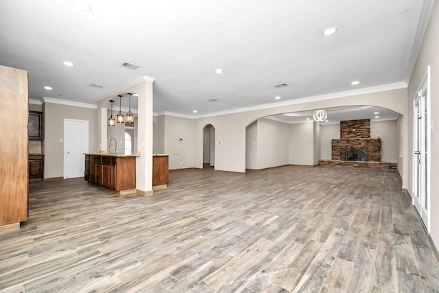 unfurnished living room with a stone fireplace, hardwood / wood-style floors, and ornamental molding