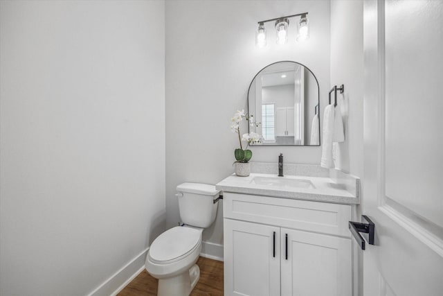 bathroom featuring toilet, vanity, and hardwood / wood-style floors