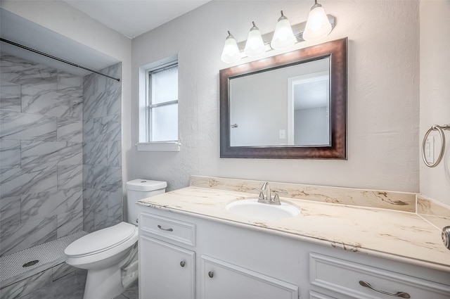 bathroom with vanity, toilet, and tiled shower