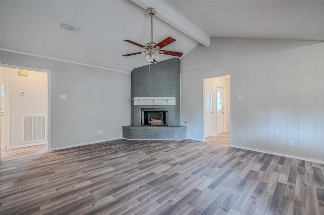 unfurnished living room with lofted ceiling with beams, ceiling fan, ornamental molding, a fireplace, and light hardwood / wood-style floors