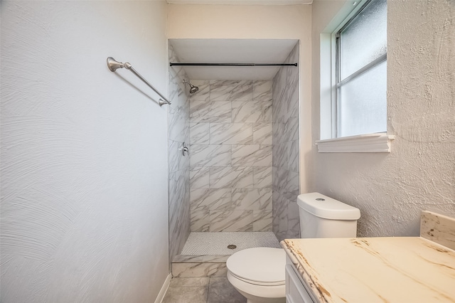 bathroom with tile patterned flooring, a tile shower, vanity, and toilet