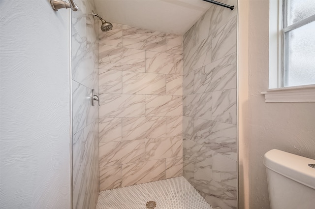 bathroom featuring a tile shower and toilet