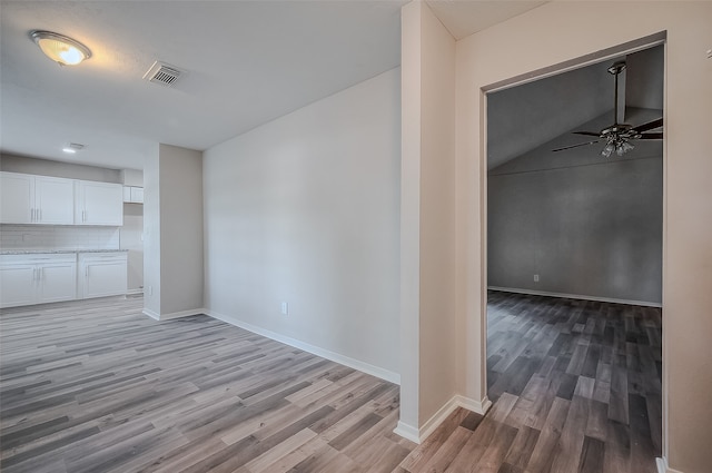 unfurnished living room with ceiling fan, vaulted ceiling, and light hardwood / wood-style flooring