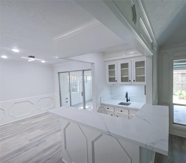 kitchen with white cabinetry, sink, hardwood / wood-style flooring, and light stone countertops