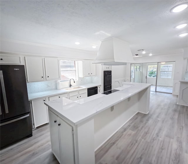 kitchen featuring black appliances, a kitchen island, light hardwood / wood-style floors, and white cabinets