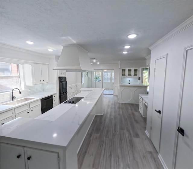 kitchen featuring a center island, white cabinets, a wealth of natural light, black appliances, and sink