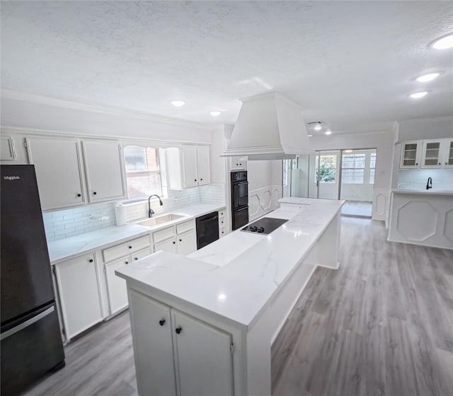 kitchen featuring a wealth of natural light, white cabinetry, sink, and black appliances