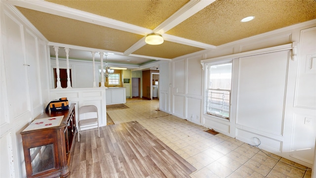 interior space featuring a wealth of natural light, a textured ceiling, a notable chandelier, and ornamental molding