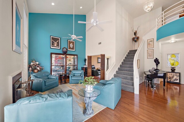 living room featuring hardwood / wood-style floors, high vaulted ceiling, and ceiling fan with notable chandelier