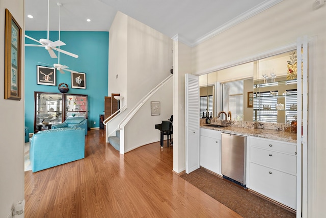 bar with sink, stainless steel dishwasher, ceiling fan, light hardwood / wood-style floors, and white cabinetry