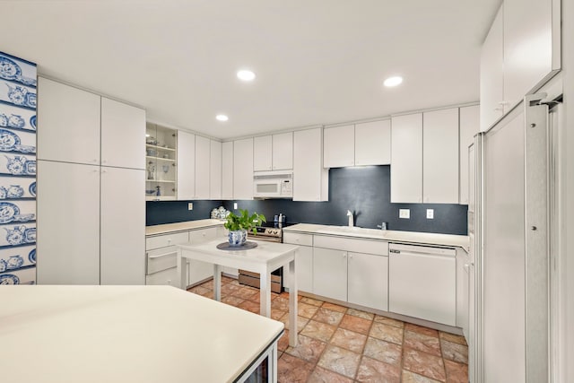 kitchen featuring decorative backsplash, white appliances, white cabinetry, and sink