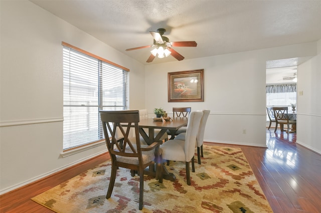 dining area with a textured ceiling, dark hardwood / wood-style flooring, a healthy amount of sunlight, and ceiling fan