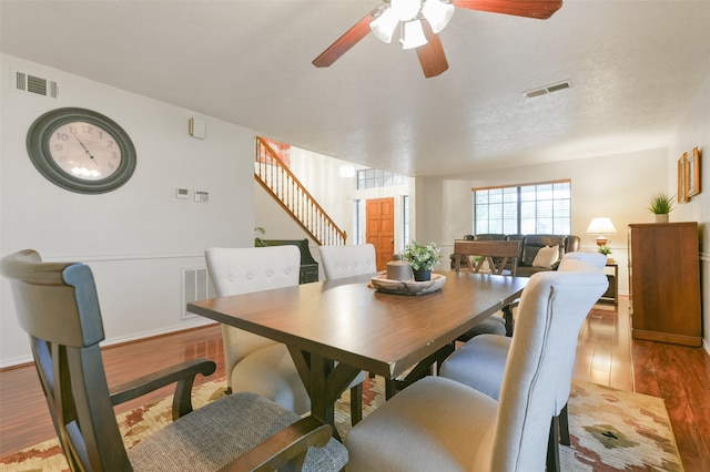 dining room with hardwood / wood-style flooring, ceiling fan, and a textured ceiling