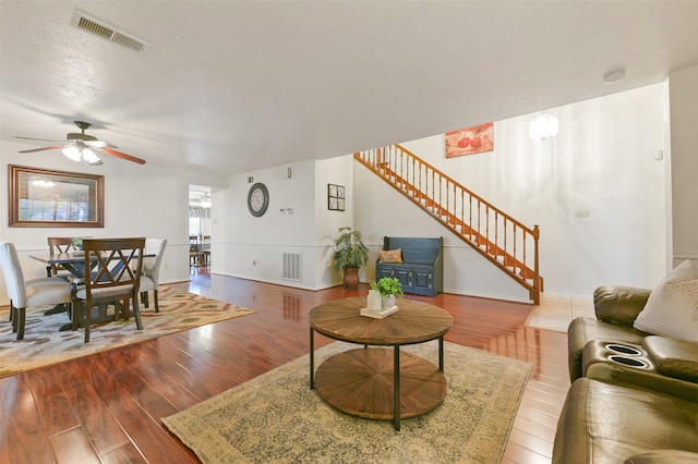 living room with ceiling fan, wood-type flooring, and a textured ceiling