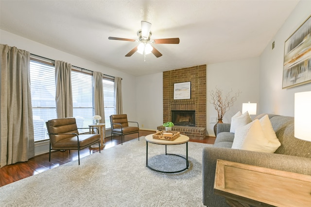 living room with a brick fireplace, dark hardwood / wood-style floors, and ceiling fan