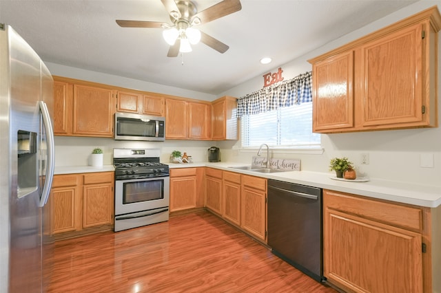 kitchen with appliances with stainless steel finishes, sink, ceiling fan, and light hardwood / wood-style flooring