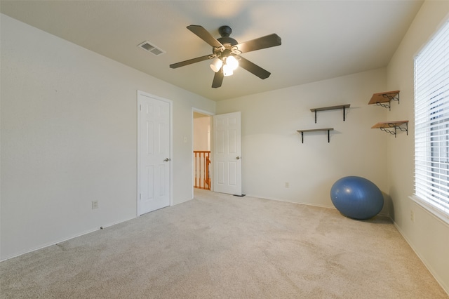 workout area with ceiling fan, plenty of natural light, and light carpet