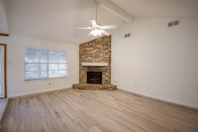 unfurnished living room featuring lofted ceiling with beams, ceiling fan, light hardwood / wood-style floors, and a brick fireplace