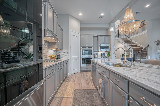 kitchen featuring gray cabinets, stainless steel appliances, sink, and decorative light fixtures