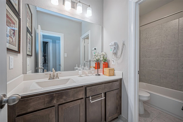 full bathroom with tile patterned flooring, vanity, tiled shower / bath combo, and toilet