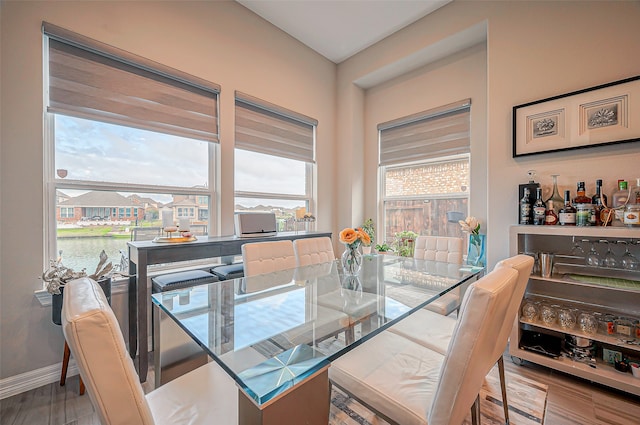 dining area with light hardwood / wood-style flooring and a water view