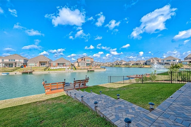 view of dock with a lawn and a water view