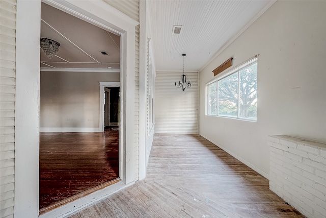 corridor with hardwood / wood-style floors, an inviting chandelier, and ornamental molding