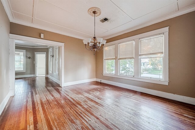 spare room with ornamental molding, hardwood / wood-style flooring, and a notable chandelier