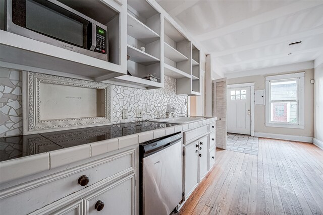 kitchen featuring sink, stainless steel appliances, tile countertops, white cabinets, and light wood-type flooring