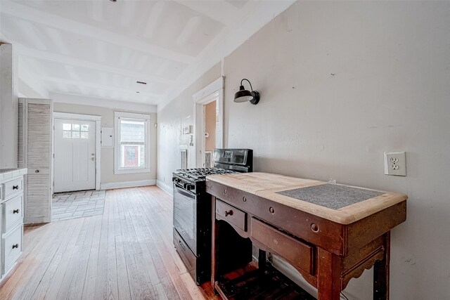 kitchen featuring beamed ceiling, black gas range oven, light wood-type flooring, and white cabinetry