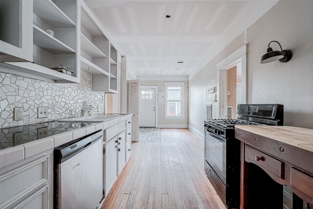 kitchen with decorative backsplash, light hardwood / wood-style flooring, dishwasher, black gas stove, and white cabinetry