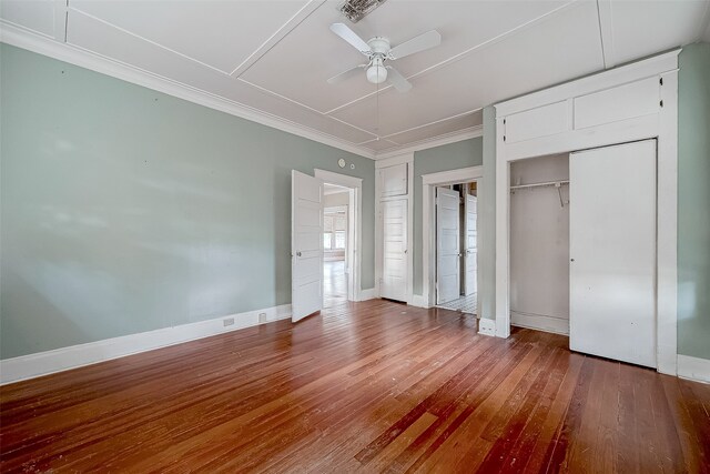 unfurnished bedroom featuring hardwood / wood-style flooring, ceiling fan, crown molding, and a closet