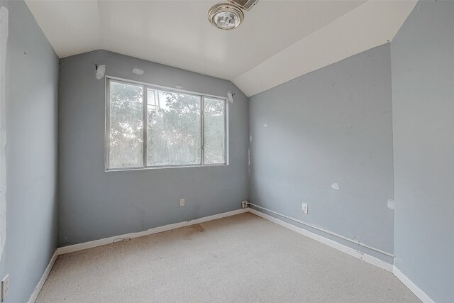 carpeted spare room with lofted ceiling