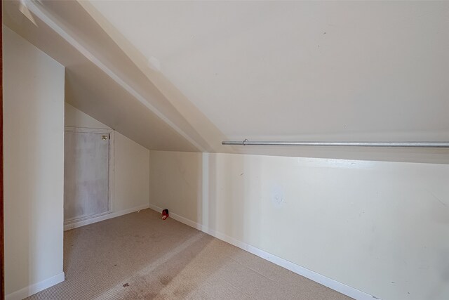 additional living space with light colored carpet and vaulted ceiling