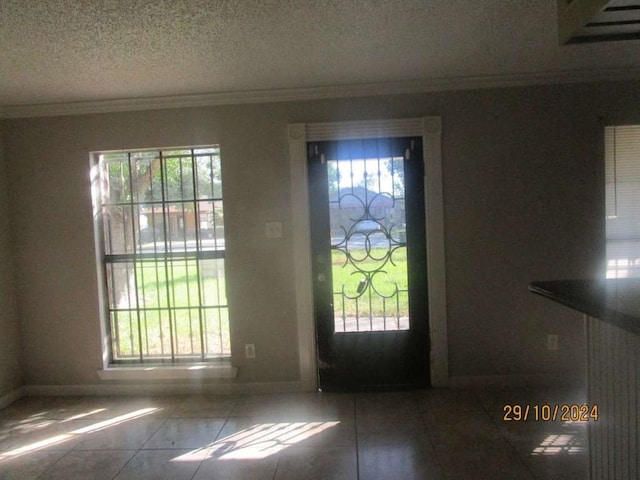 entrance foyer featuring a textured ceiling, tile patterned flooring, a healthy amount of sunlight, and crown molding