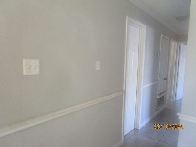 hall with tile patterned flooring and crown molding