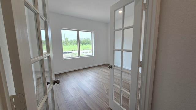 unfurnished room featuring french doors and light hardwood / wood-style flooring