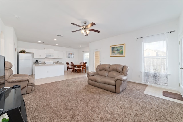 living room with light colored carpet, ceiling fan, and plenty of natural light