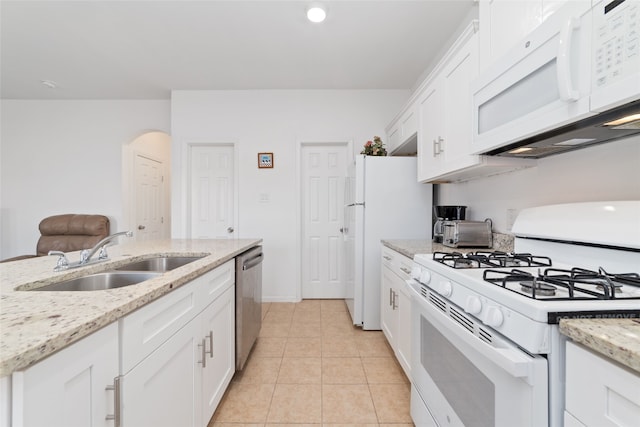 kitchen with light tile patterned floors, light stone countertops, sink, white cabinets, and white appliances