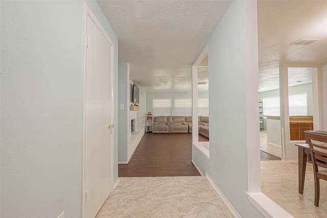 hallway with a textured ceiling and light hardwood / wood-style floors