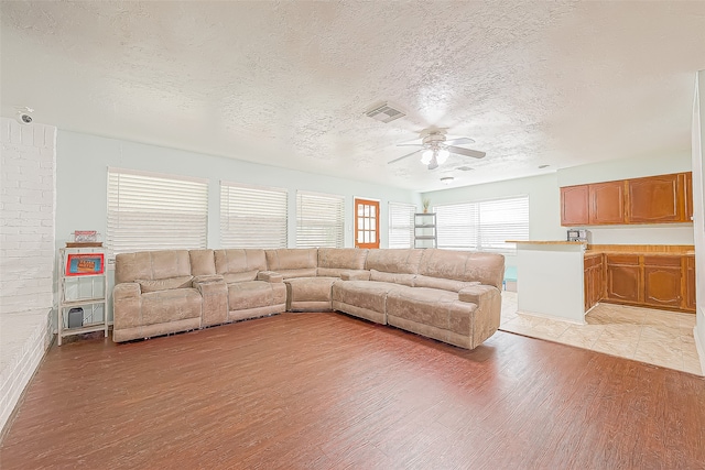 unfurnished living room with a textured ceiling, ceiling fan, and light hardwood / wood-style flooring