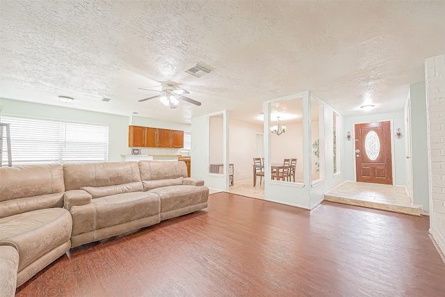 unfurnished living room featuring hardwood / wood-style floors, ceiling fan with notable chandelier, and a textured ceiling