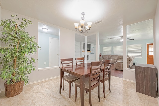 dining space featuring ceiling fan with notable chandelier