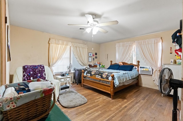 bedroom featuring hardwood / wood-style floors, cooling unit, and ceiling fan