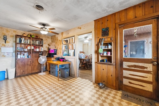 kitchen with a textured ceiling, wooden walls, and ceiling fan