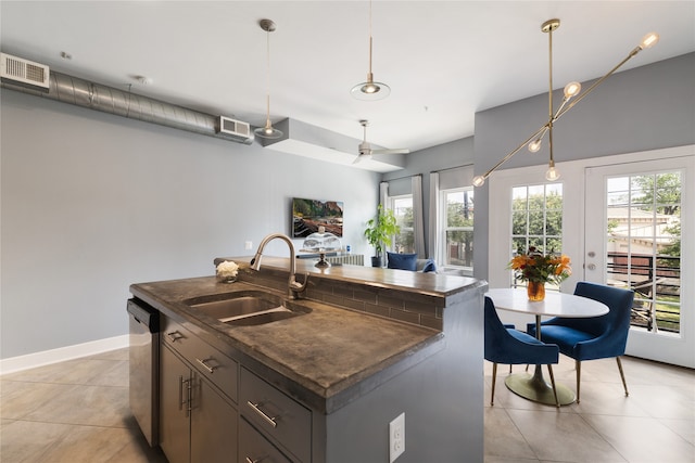 kitchen featuring a kitchen island with sink, decorative light fixtures, sink, and dishwasher