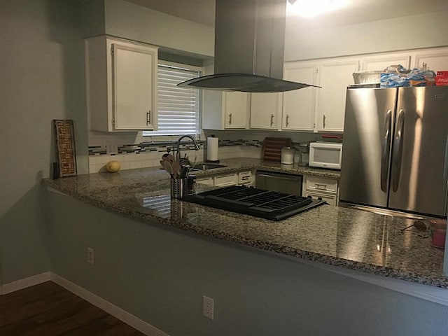 kitchen with dark stone counters, sink, island exhaust hood, white cabinetry, and appliances with stainless steel finishes