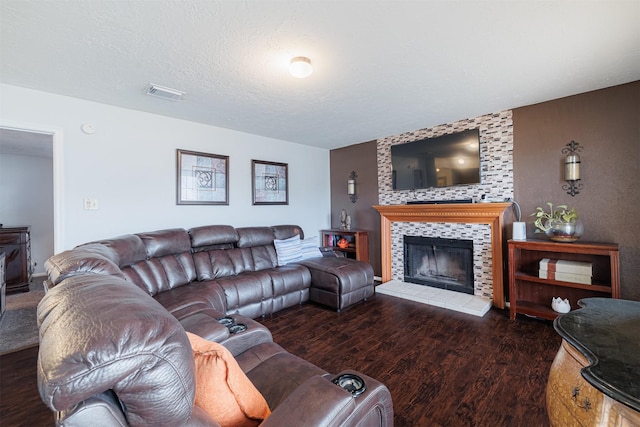 living room with dark hardwood / wood-style floors, a textured ceiling, and a tiled fireplace