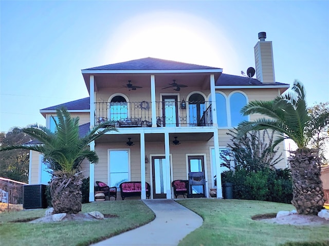 back of property featuring a yard, ceiling fan, and a balcony